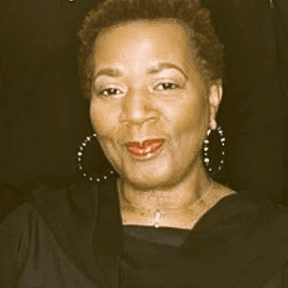 Close-up portrait of a smiling Black woman with short hair and large hoop earrings.